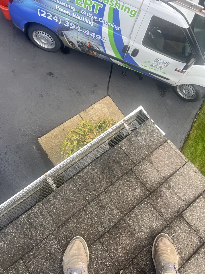 Gutter guard reinstalled on a gutter corner after cleaning, seen from the roof of a Libertyville home with the Window Washing Expert van in the driveway
