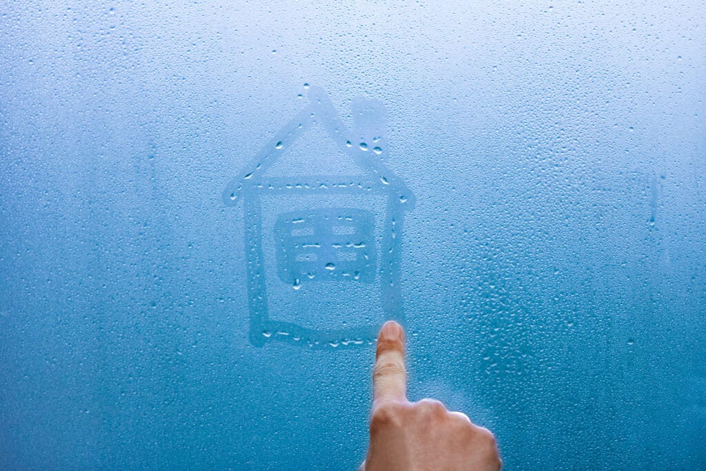 person draws a house on a glass window 