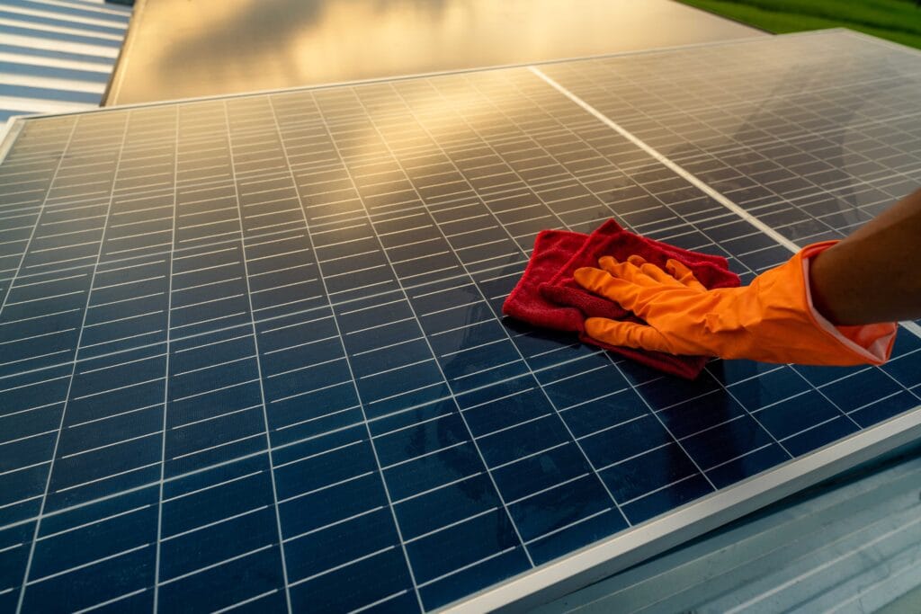 Man cleaning solar panel on roof
