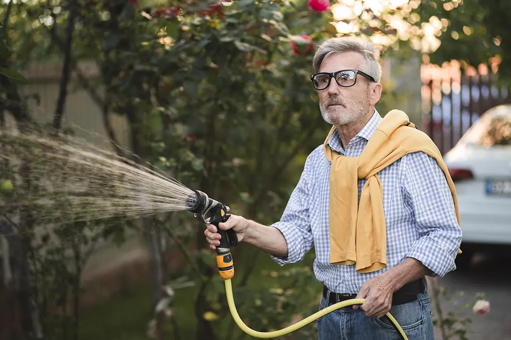 man washing his house with water stream 
