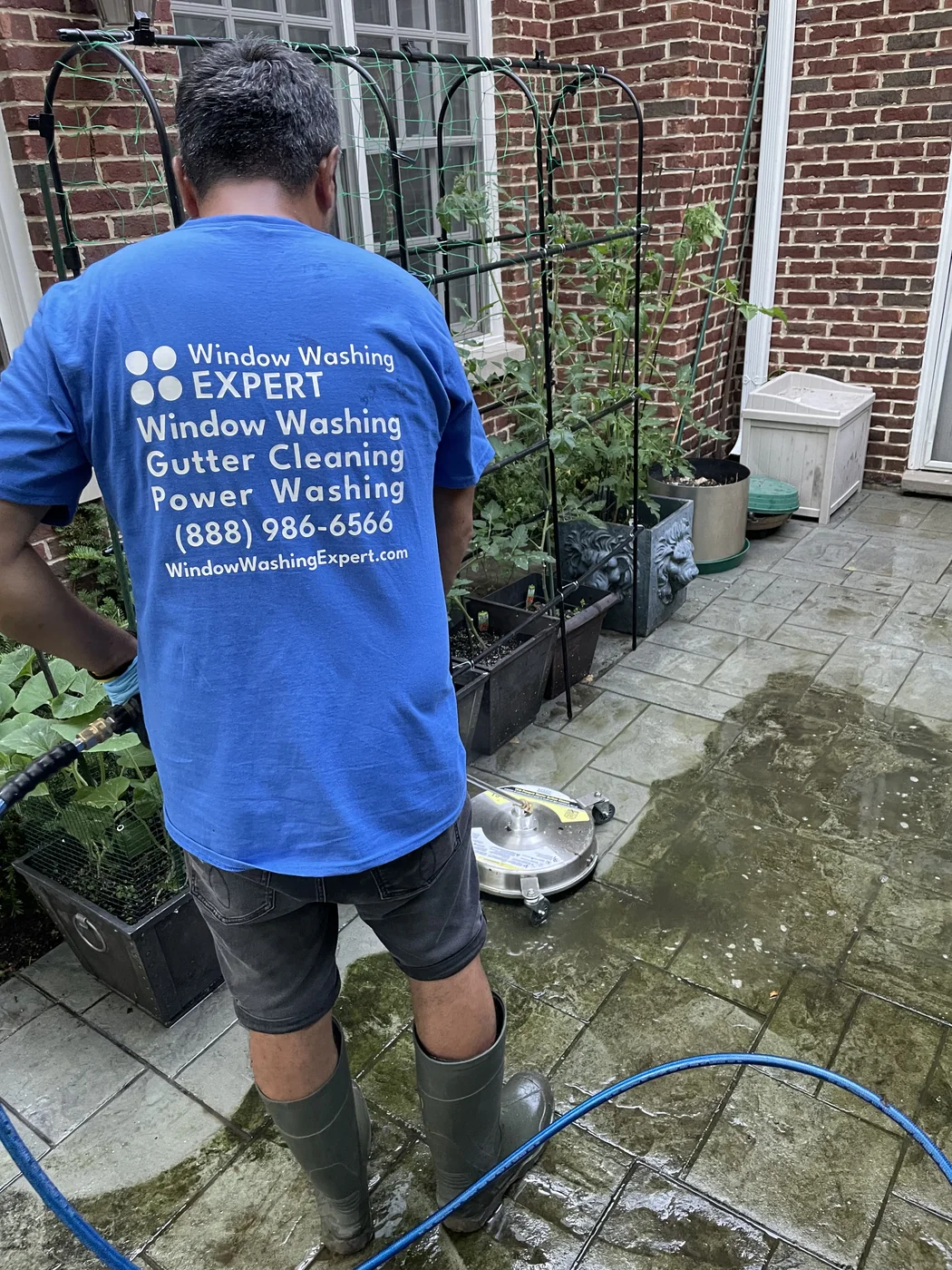 technician power washing a brick and stone paver patio